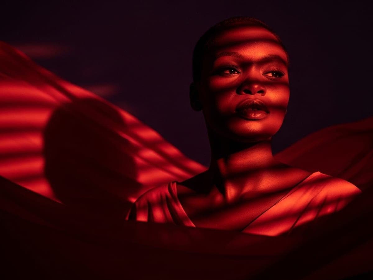 A woman lit in deep red, mid sentence, her expression unguarded